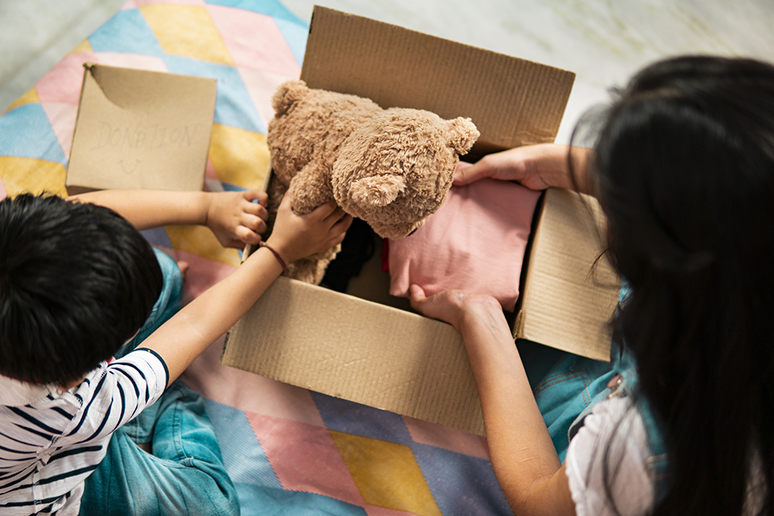 two kids packing clothes and toy into a donation box